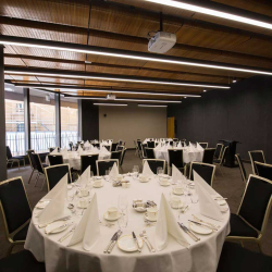 Banquet hall set with round tables covered in white linens, folded napkins, and formal place settings ready for a event.
