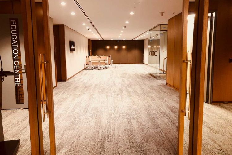 Neutral, well-lit education center hallway with wooden frames, glass doors, and a sign reading 'EDUCATION CENTRE' on the left.