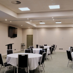 Banquet-style conference room with round tables covered in white cloths and black chairs around them.